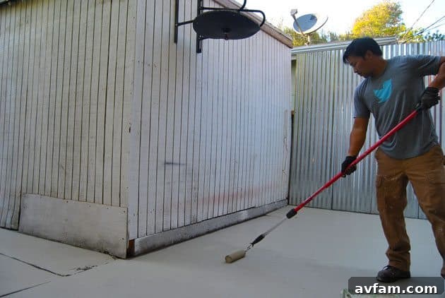 A person applying Olympic Rescue It resurfacer to a patio with a roller and an extension pole