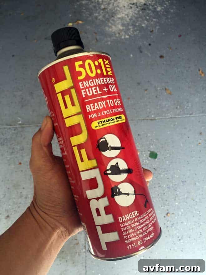 TRUFUEL: Ready to Power Your Outdoor Tasks An open can of TRUFUEL 50:1 Fuel nestled in lush green grass beside a garden tool, symbolizing fresh fuel ready for use in outdoor power equipment.