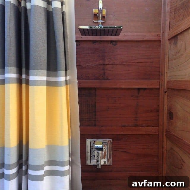 Outdoor shower with a dark stone privacy wall and pebble flooring