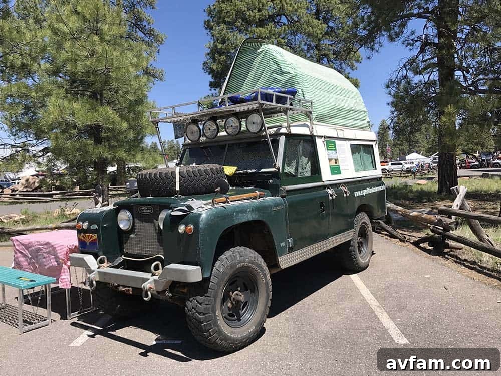 A white overland SUV, possibly a Lexus GX, with a large rooftop tent, awning, and other expedition essentials.