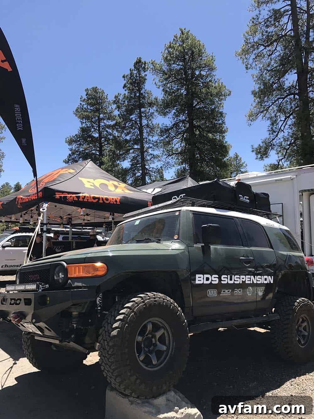 A black Ford F-Series pickup truck with an elaborate bed-mounted camper, featuring solar panels and external storage.