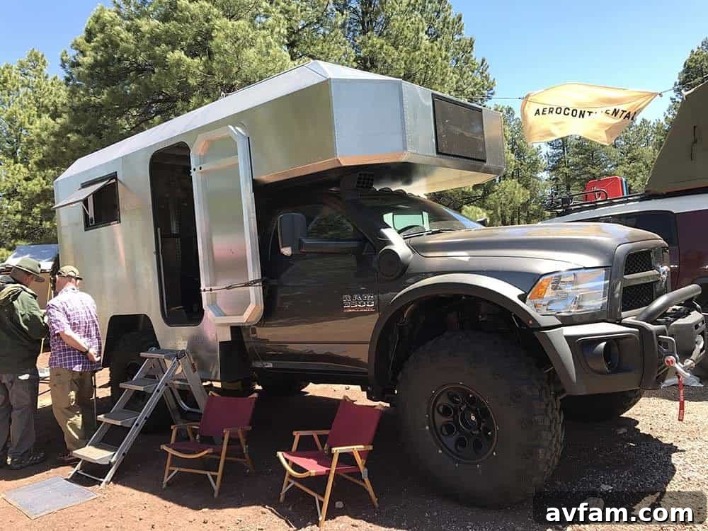 A yellow and black customized Jeep Wrangler, featuring heavy-duty off-road modifications and a rooftop tent.