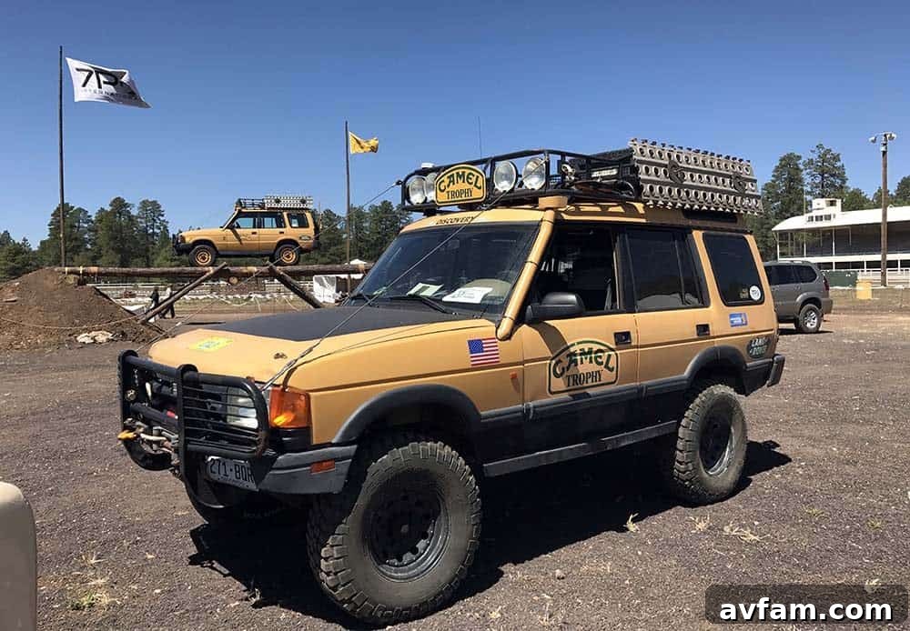 A custom overland truck with a distinctive blue and white paint job, equipped with a roof rack and auxiliary lights.