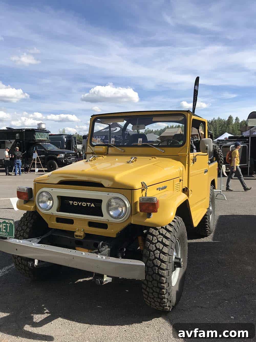 A close-up view of an overland vehicle's rear, showing a swing-out tire carrier and additional fuel/water storage.
