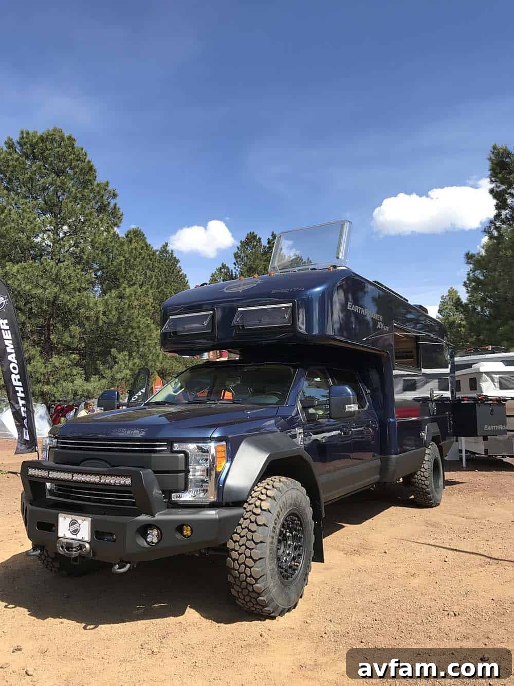 A custom flatbed overland truck, featuring a sturdy canopy and organized external storage for equipment.