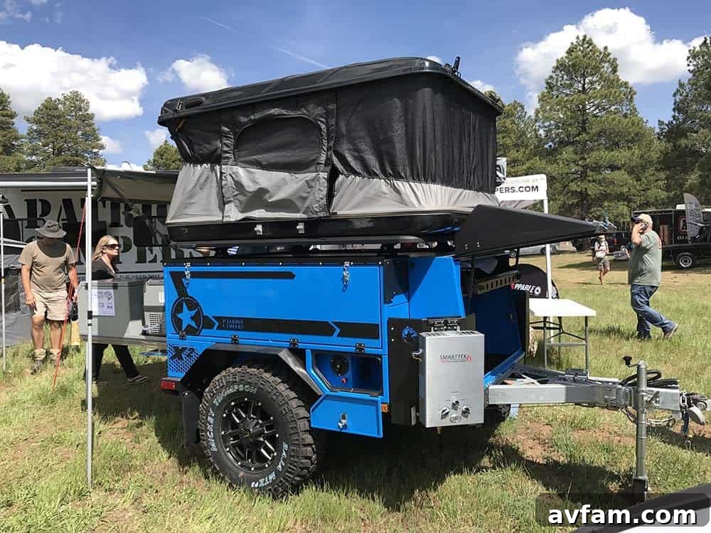 A yellow and black customized Jeep Wrangler with a rooftop tent and extensive off-road armor, prepared for tough trails.