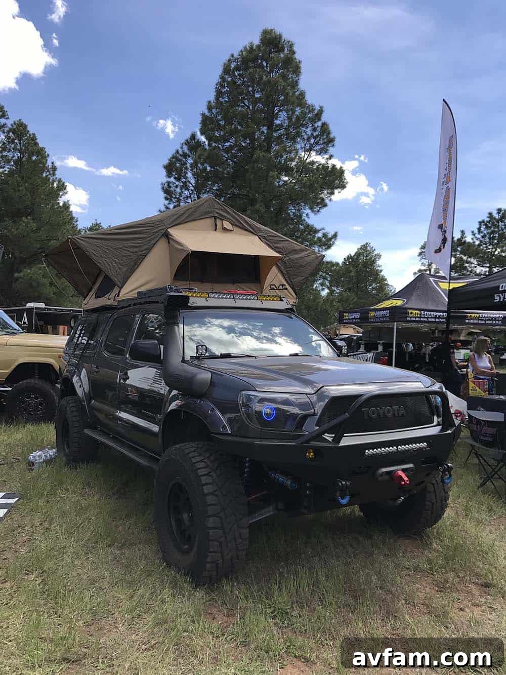 A white modern full-size pickup truck with a large, elevated camper unit, showcasing ample living space for overlanding.