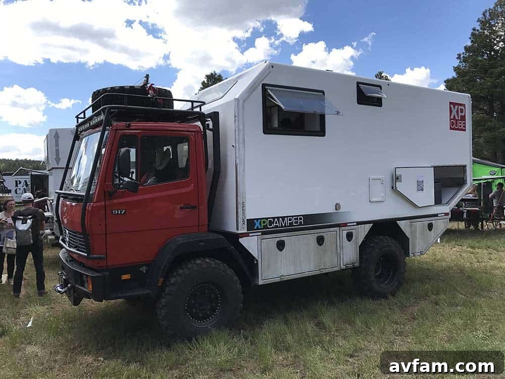 A blue Jeep Wrangler with a flatbed conversion and a compact camper, offering a unique and versatile overland platform.