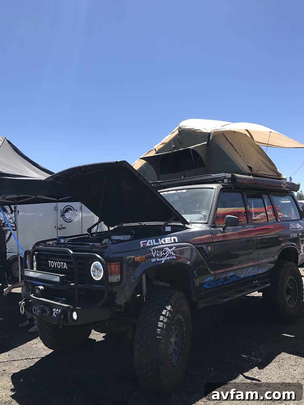 A unique overland vehicle with a bespoke camper shell, parked among other rigs, highlighting custom fabrication for adventure travel.