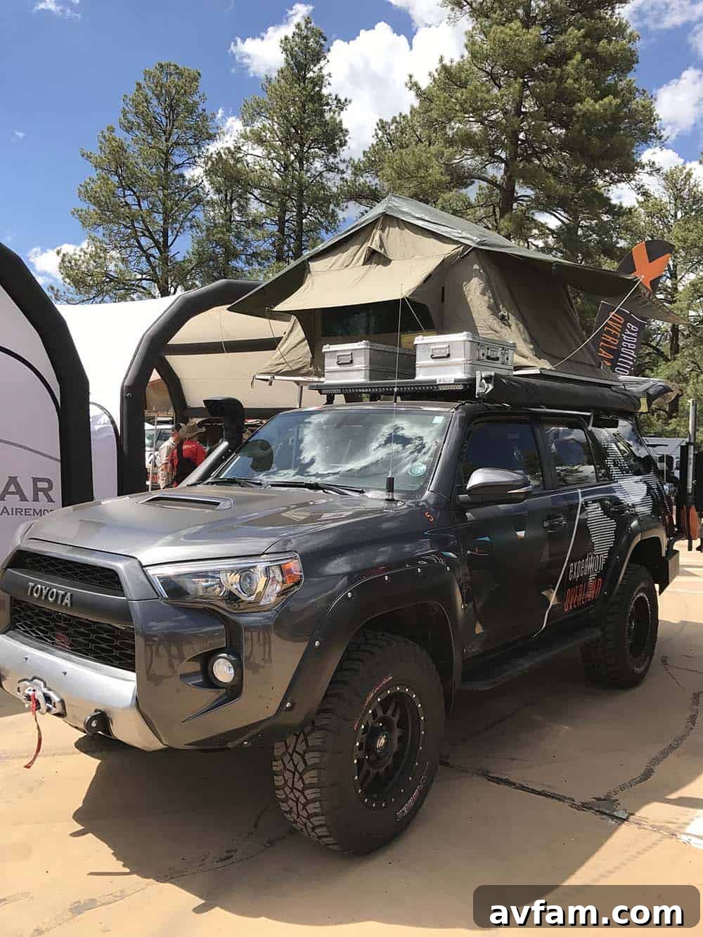 A gray Toyota Tundra pickup truck with a compact, aerodynamic wedge-style camper, designed for efficient travel.
