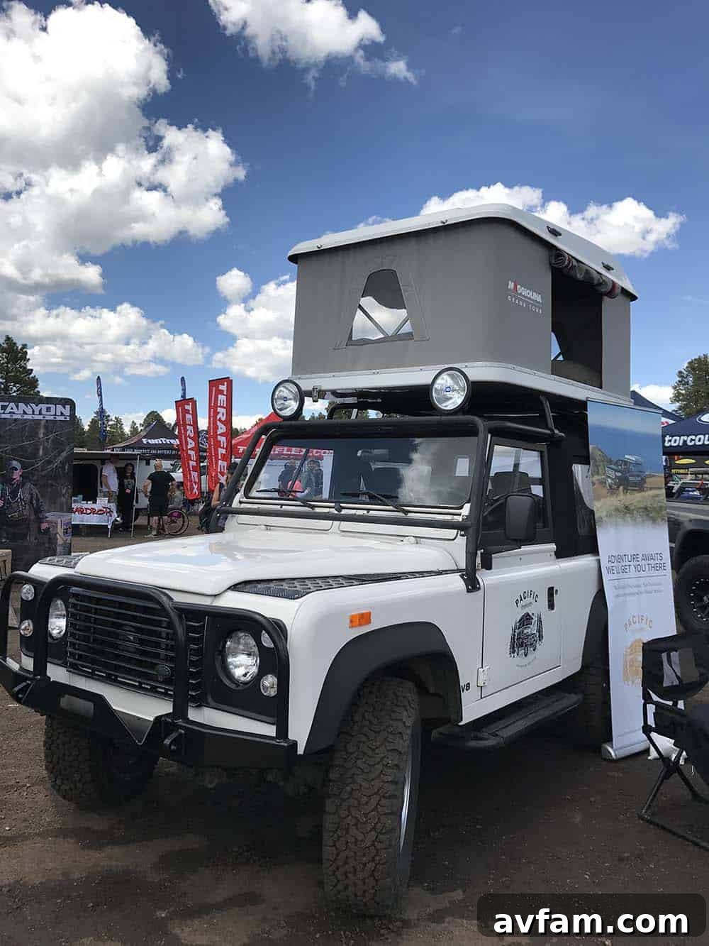 A black Jeep Wrangler with a hard-shell rooftop tent deployed, ready for immediate camping.