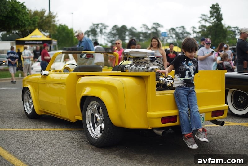 A vintage custom Chevrolet or Ford pickup truck, painted in a striking teal color with chrome accents and a lowered suspension, showcased at an event.