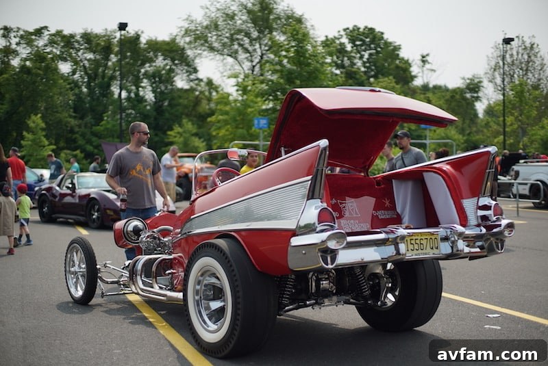 A wide shot of a classic custom car painted in a deep red, with a powerful V8 engine exposed and polished chrome details, at an outdoor car show.