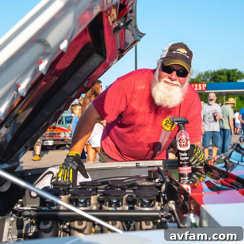 A full-body shot of a vintage American pickup truck, heavily customized with a lifted suspension, large off-road tires, and a rugged, industrial aesthetic, at a Hot Wheels event.
