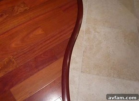 Innovative Curved Wood-to-Tile Flooring Transition Elegant curved flooring transition between light wood and dark tile, showcasing innovative design in an open-plan home.