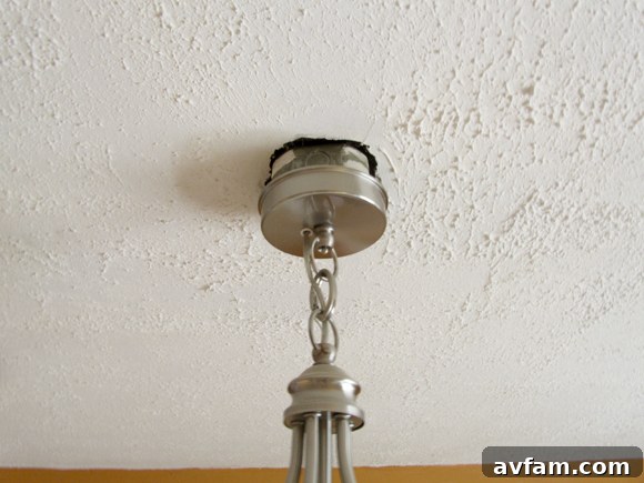 Close-up view of the protruding electrical junction box with a modern light fixture, highlighting the gap and exposed edges.