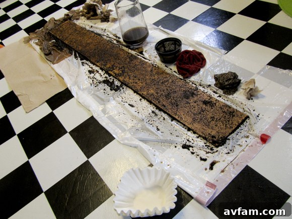 The wooden plank for the giant ruler being naturally stained with coffee grounds, showcasing an environmentally friendly method to achieve an aged, rustic wood finish. The grounds are evenly spread across the surface.