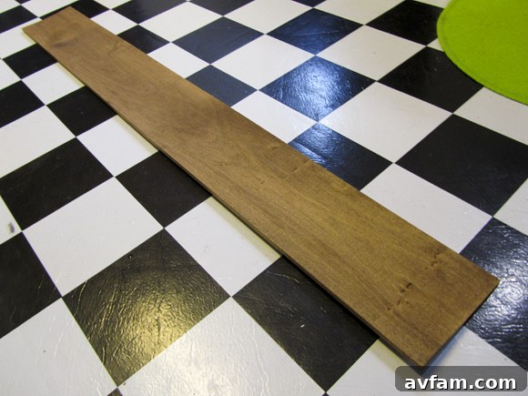 The giant ruler plank fully dried after the natural coffee grounds staining, displaying a rich, aged wood finish that enhances its rustic appeal before any further markings or numbers are added.