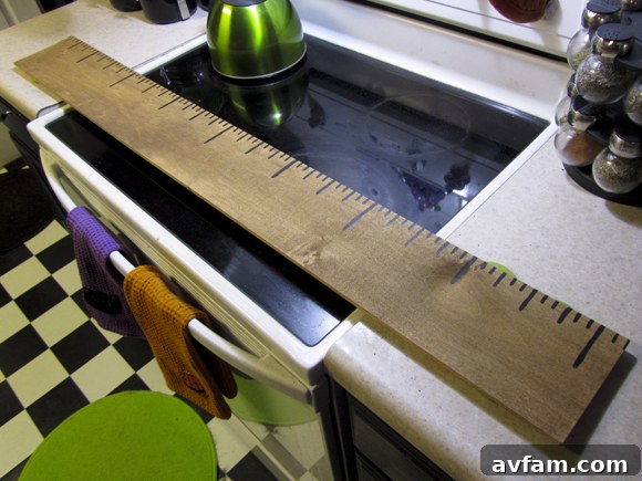 The process of adding detailed measurement markings to the giant ruler, demonstrating the use of a standard ruler and a fine paintbrush to ensure accuracy and neatness in the lines.