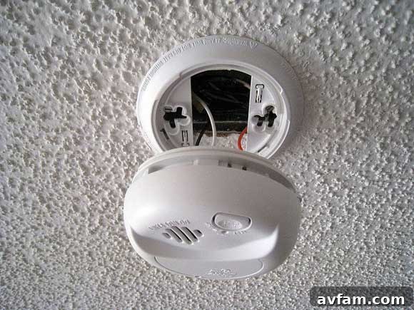 Ensuring Your Smoke Detector is Ready: A Crucial Step for Home Safety Hand replacing battery in a modern smoke detector, symbolizing essential home fire safety and timely maintenance