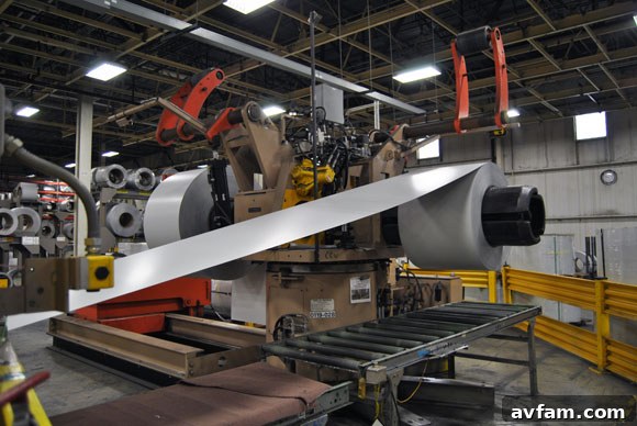 A large spool of steel being unwound for garage door production.