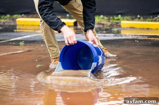 Another perspective of the Quiklid in action as a water scoop, emphasizing its wide mouth and ergonomic use for effective spill management.