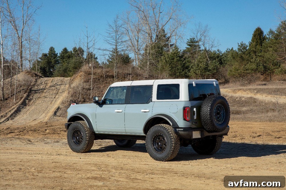 A panoramic shot of the Ford Bronco driving on a dirt road in a vast landscape.