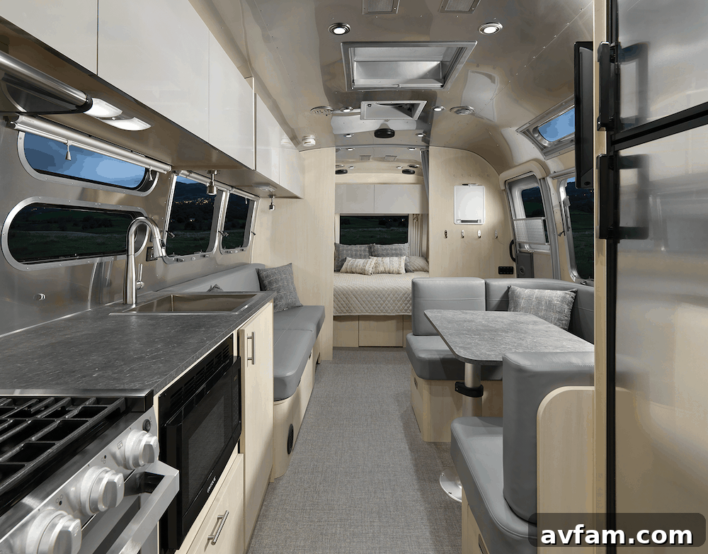 A wider view of the Airstream Flying Cloud 30FB Office interior, showing the queen bed, dinette, and the office space in context, ideal for families.