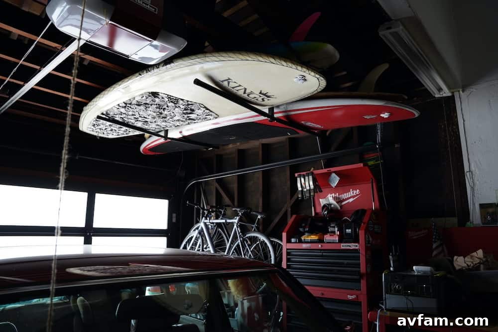 Multiple surfboards and standup paddleboards neatly stored on a hanging garage rack, showing excellent organization