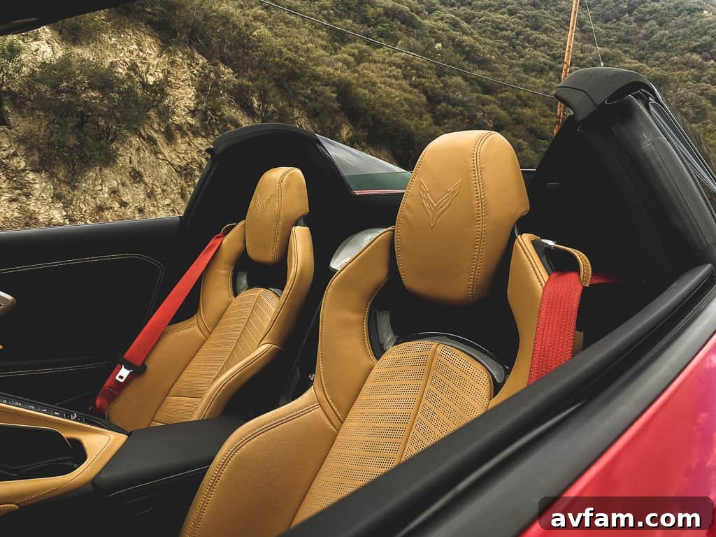 Red 2020 Corvette C8 Convertible driving along a scenic coastal road with the top down, showcasing its elegant profile.