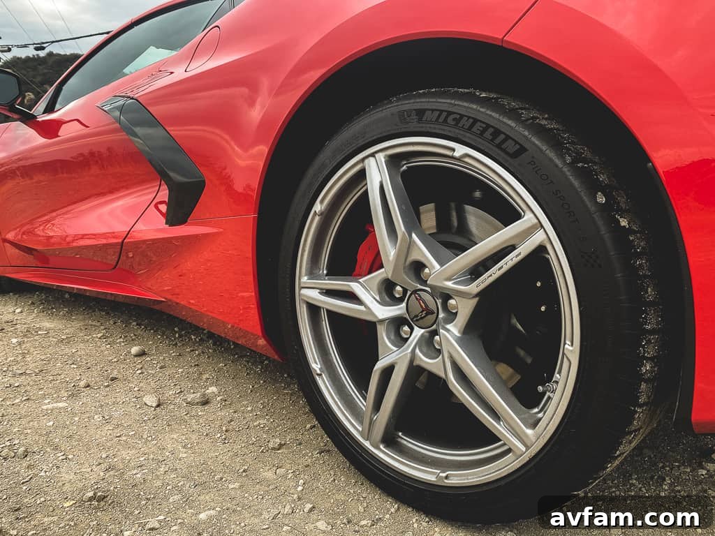 The rear view of the red Corvette C8 Convertible with its retractable hardtop deployed, parked against a vibrant green landscape.