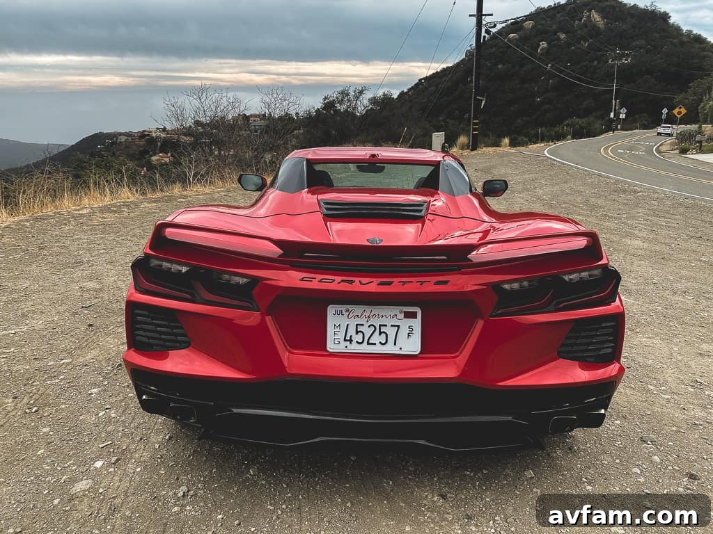 Dynamic shot of the 2020 Corvette C8 Convertible speeding along a coastal highway, showcasing its sleek side profile.