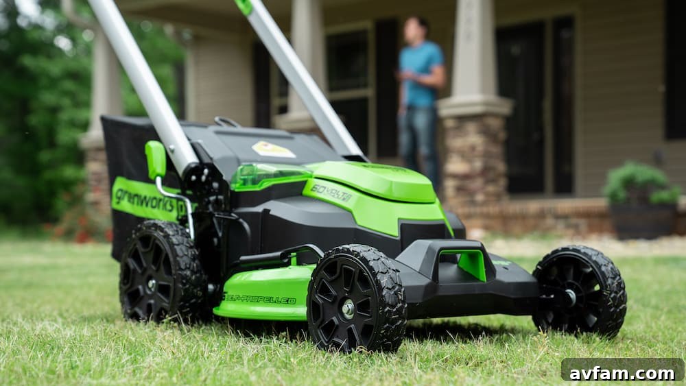 Greenworks Cordless Lawn Mower in Action A person pushing a Greenworks 60V cordless lawn mower across a lush green lawn, demonstrating efficient and quiet operation.