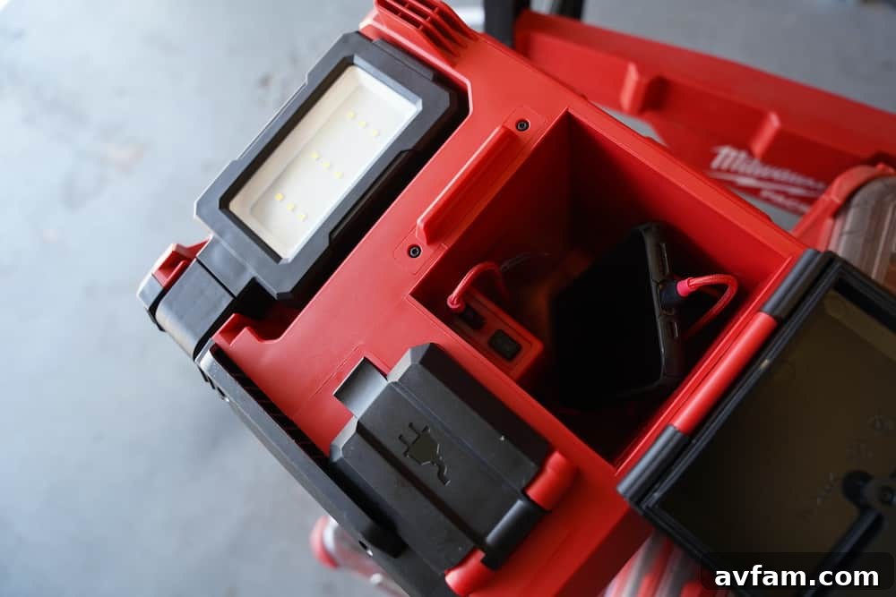 Milwaukee M18 Packout Light with a phone charging via its USB port.