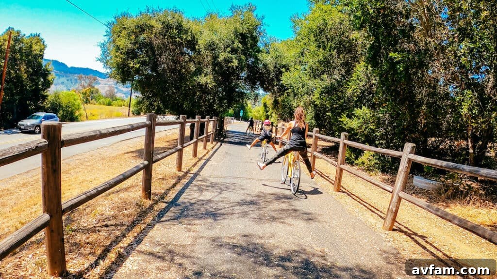 A family enjoying bike riding on the scenic Ojai Valley Trail, with lush greenery and mountains in the background.