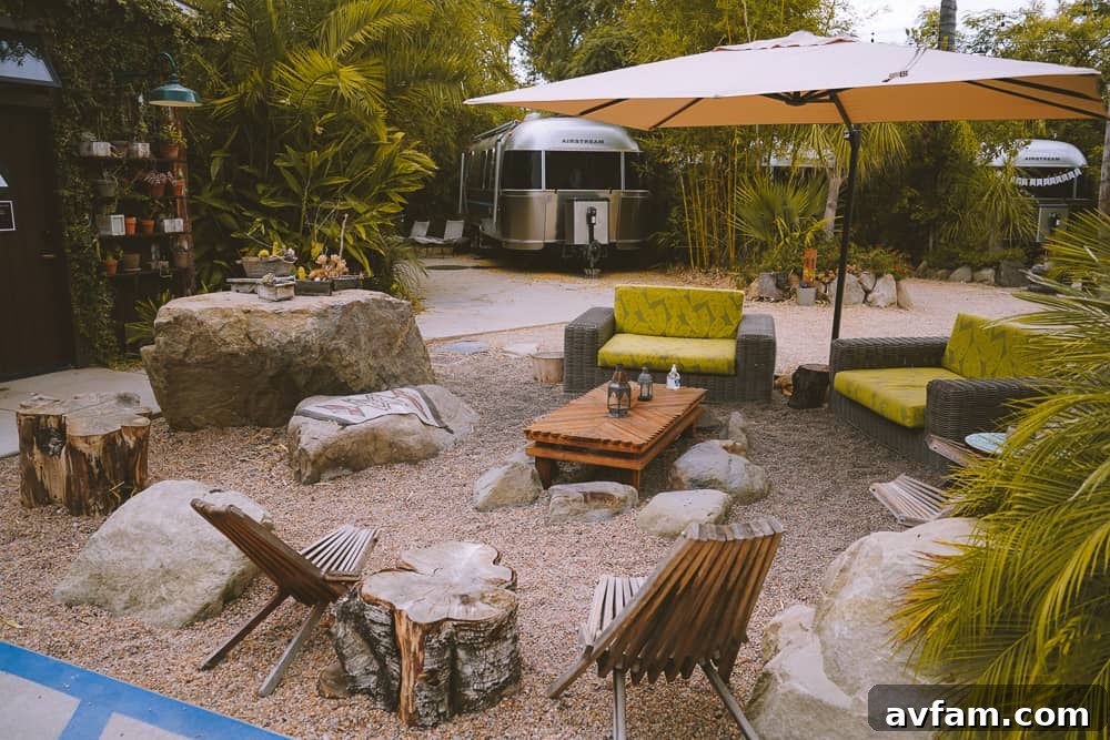 A cozy outdoor seating area next to an Airstream, shaded by trees, perfect for quiet moments.
