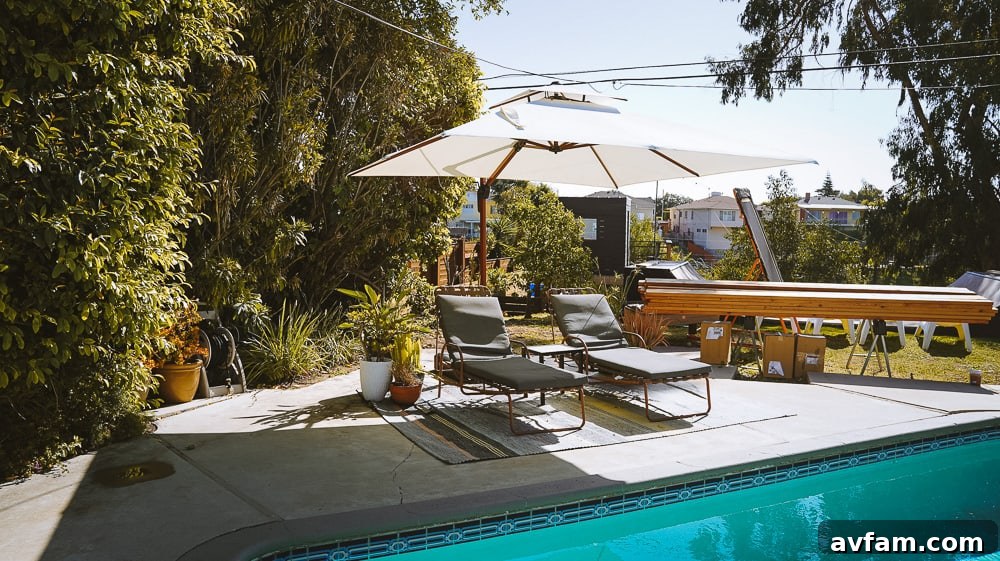 Current poolside seating area with an outdoor rug on a concrete patio before deck construction