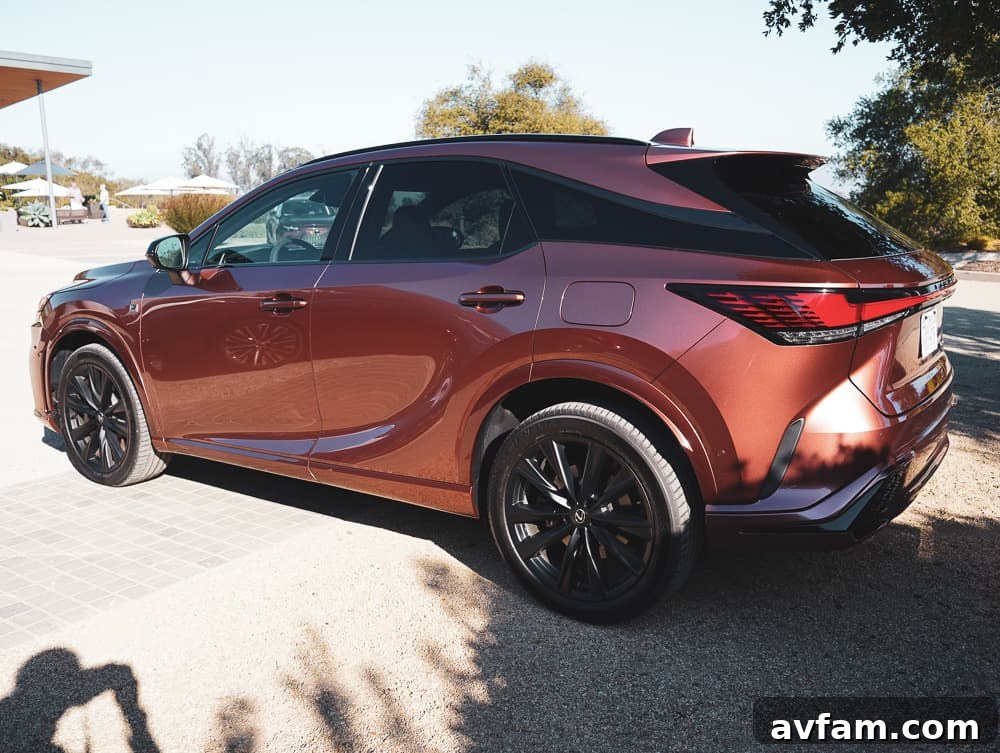 Dynamic shot of the 2023 Lexus RX 500h F Sport Performance passing by trees.