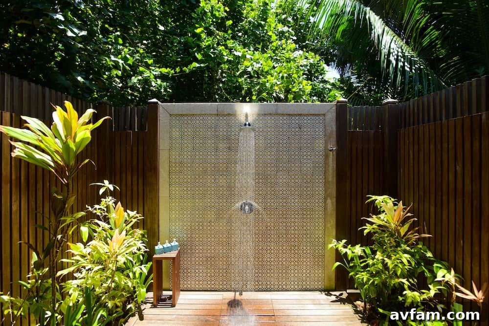 A minimalist outdoor shower with concrete walls and a dark wooden bench, showcasing contemporary cool design.