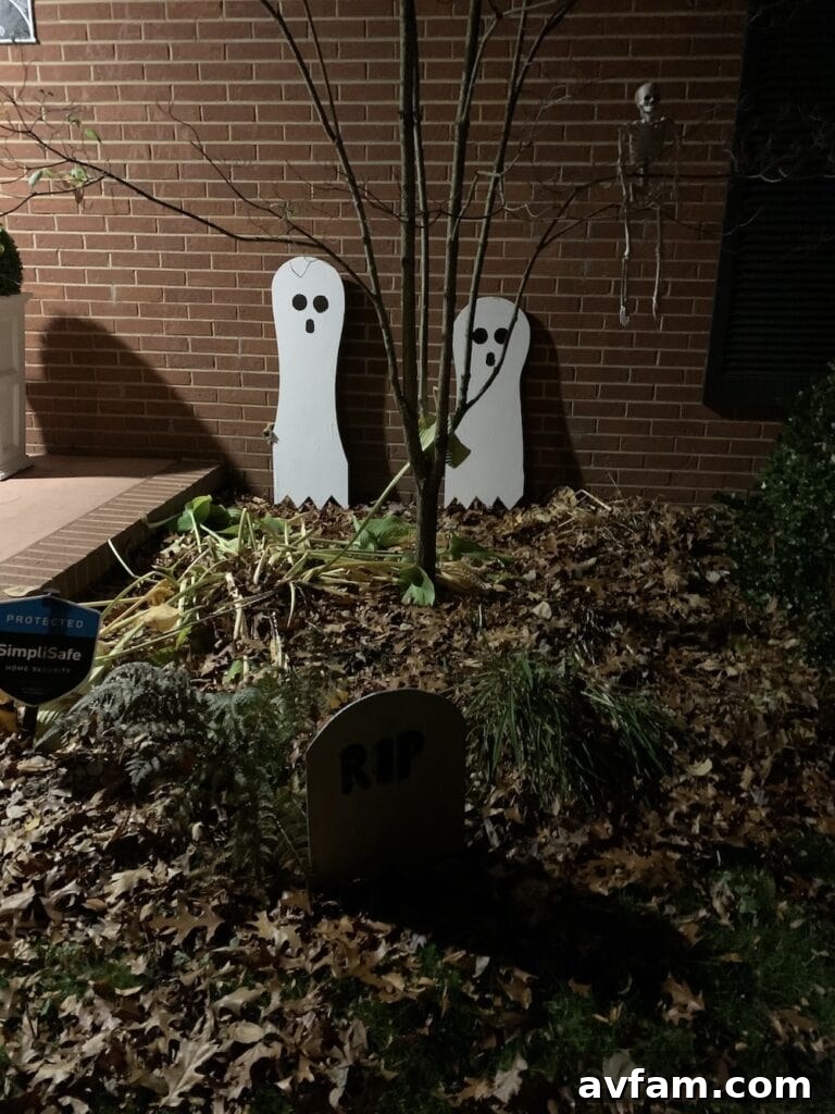 Detailed Ghost and Tombstone Decor Closer view of three ghost figures and tombstones in a Halloween yard scene