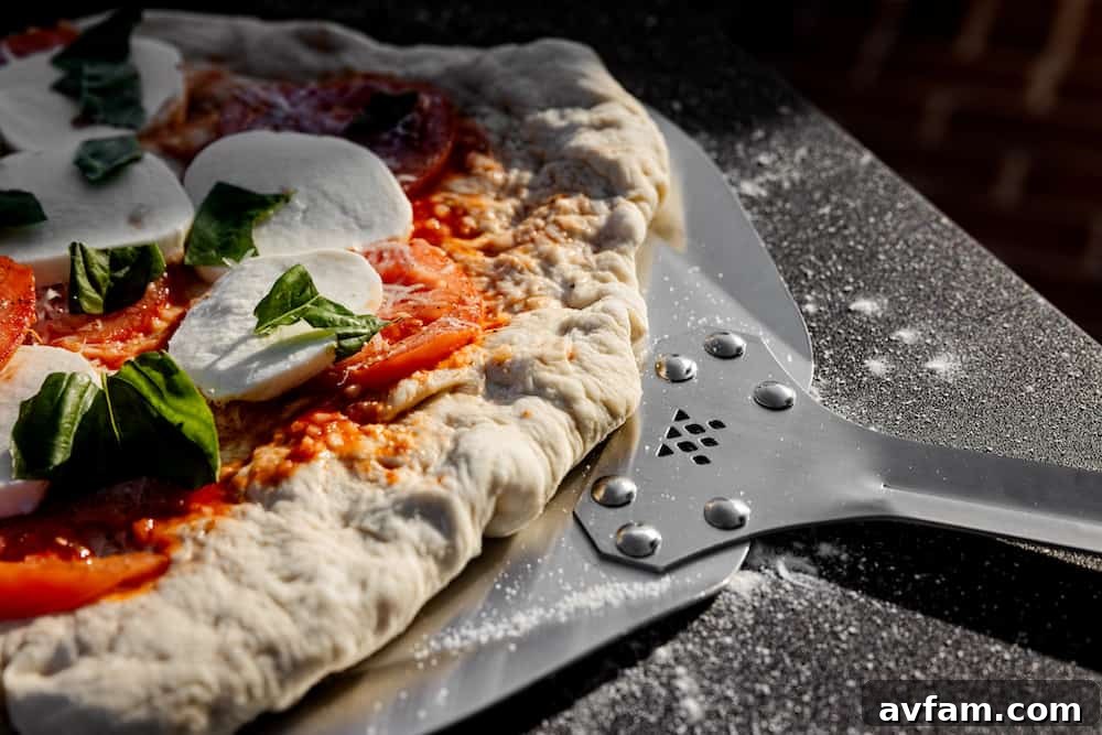 Homemade pizza dough being prepared on a wooden cutting board, ready for toppings.