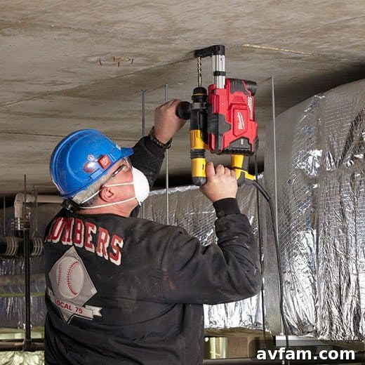 Milwaukee M12 HAMMERVAC Universal Dust Extractor attached to a rotary hammer, demonstrating on-site dust capture