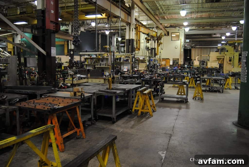 An assembly line technician meticulously working on a John Deere utility vehicle chassis