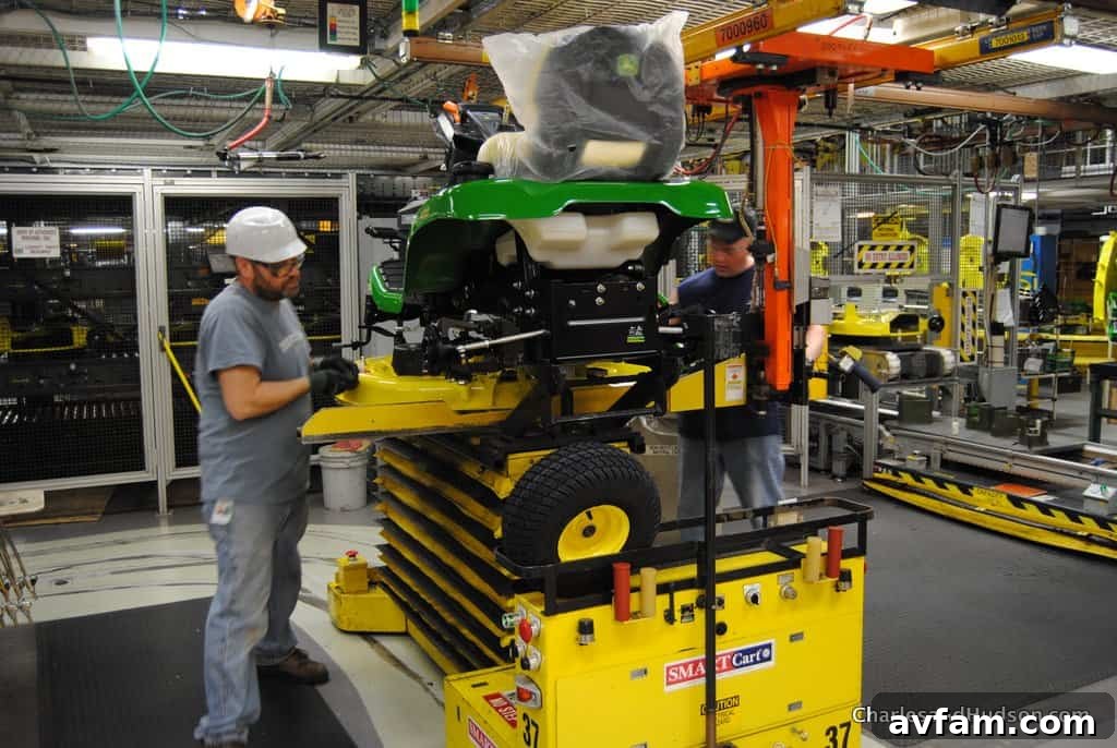 A John Deere worker proudly showcasing a newly assembled part