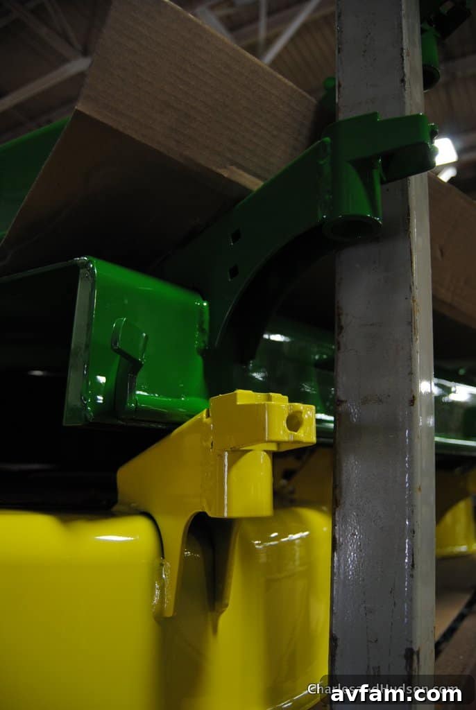 A worker conducting a visual inspection of a John Deere riding mower