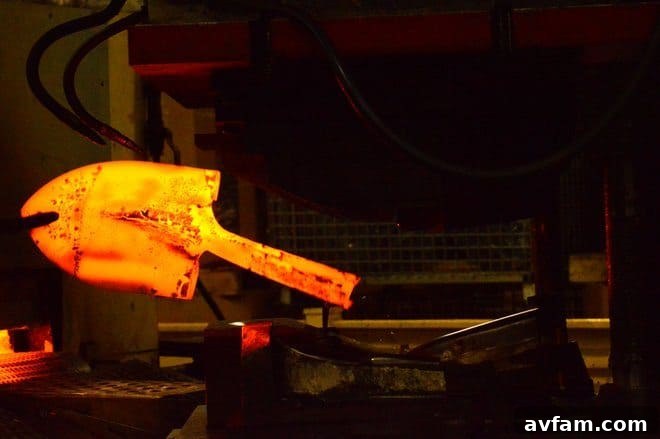 Intense glow of a red-hot steel blade being shaped with precision during the manufacturing process at The AMES Companies