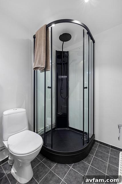 A small puddle of water on the bathroom floor outside a glass shower door.