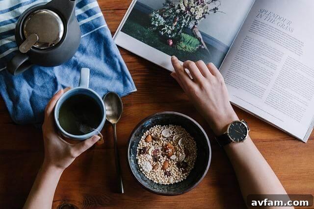 Shake Up Your Steep With 7 New International Tea Day Traditions 3 A person enjoying a healthy breakfast of cereal and fruit while reading a book at a wooden table