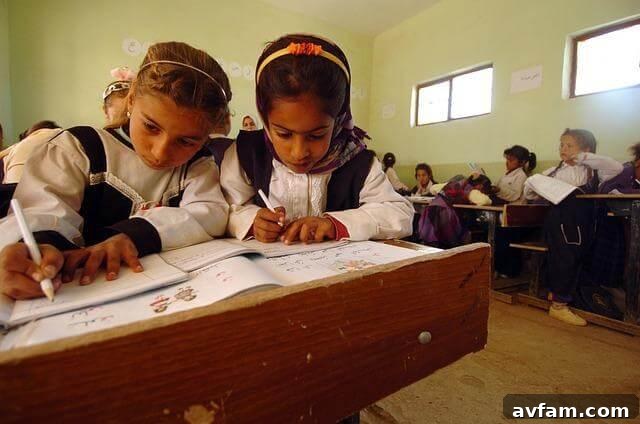 Two young girls learning and writing in a classroom