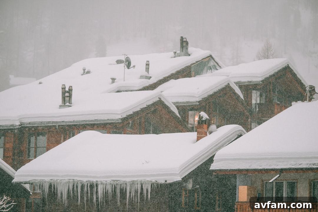 A snow-covered house with long icicles hanging from the roof edge in winter